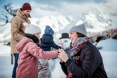 Übergossene Alm - Familie mit Kinder beim Schneemann bauen