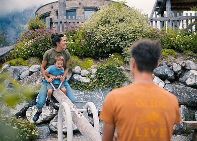 Übergossene Alm - Outdoor Almspielplatz Familie mit Kind beim Wippen