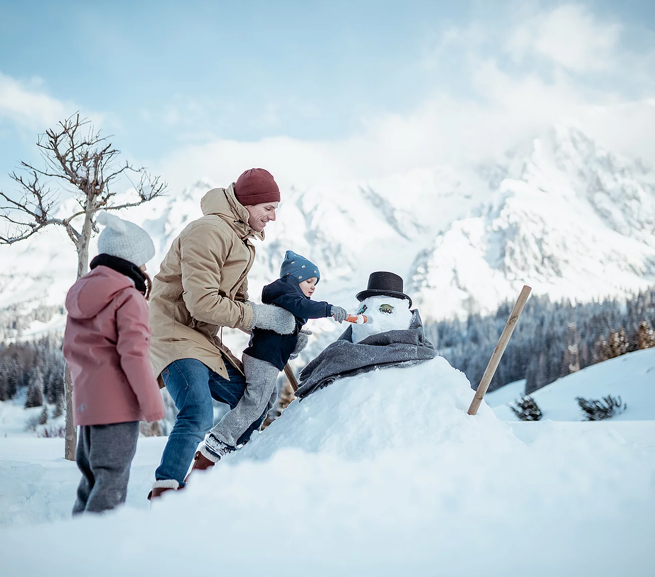 Übergossene Alm - Vater mit Kindern beim Schneemann bauen