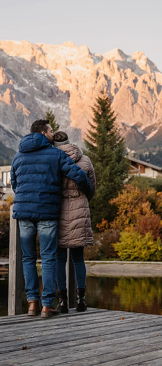 romantik-uebergossene-alm-resort-salzburg-012 Mann und Frau umarmen sich vor der Naturkulisse Hochkönig und Almsee im Herbst