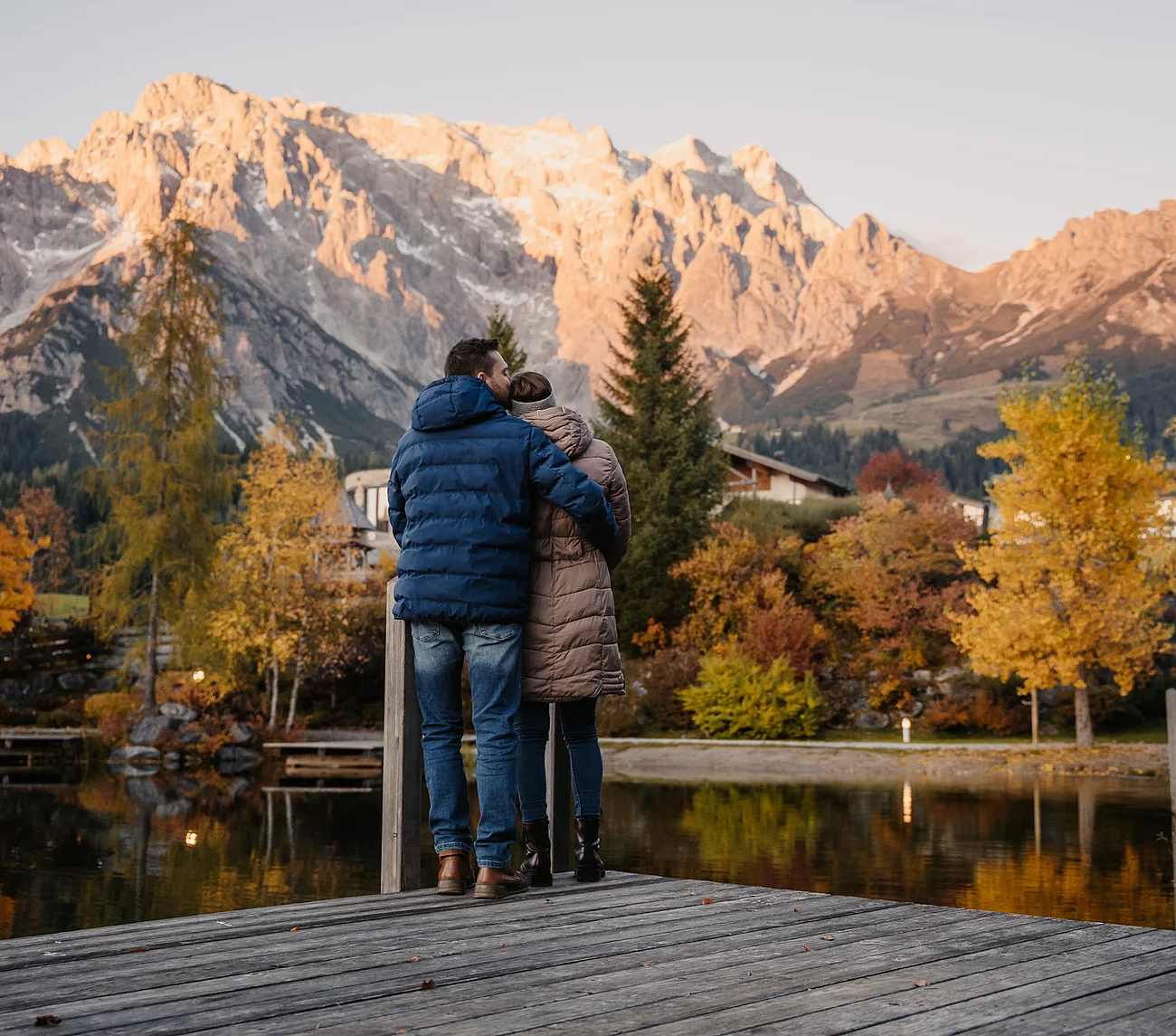 romantik-uebergossene-alm-resort-salzburg-012 Mann und Frau umarmen sich vor der Naturkulisse Hochkönig und Almsee im Herbst