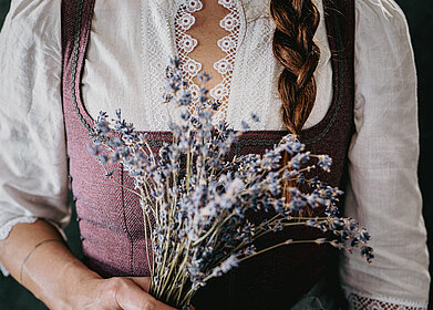 Frau im Dirndl mit Blütenstrauß in der Hand – traditionelle Kleidung im Übergossenen Alm Resort