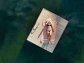 Übergossene Alm - Frau auf Steg im Badesee