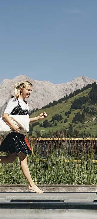 Übergossene Alm - Frau im Dirndl lauft um den Almsee