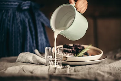 Übergossene Alm - Kellnerin schenkt Milch in Glas ein