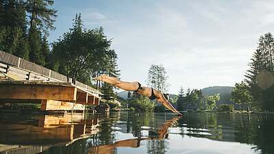 Übergossene Alm - Frau springt in Badesee