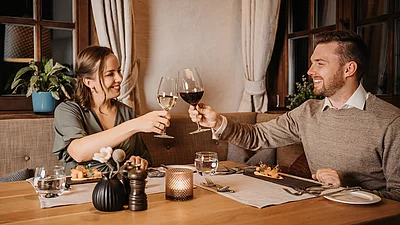 romantik-urlaub-uebergossene-alm-resort-011 Frau und Mann bei gemeinsamen Abendessen und Anstoßen mit Weingläsern