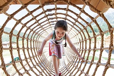Übergossene Alm - Outdoor Almspielplatz Kind im Kletterdurchgang
