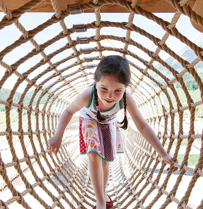 Übergossene Alm - Outdoor Almspielplatz Kind im Kletterdurchgang